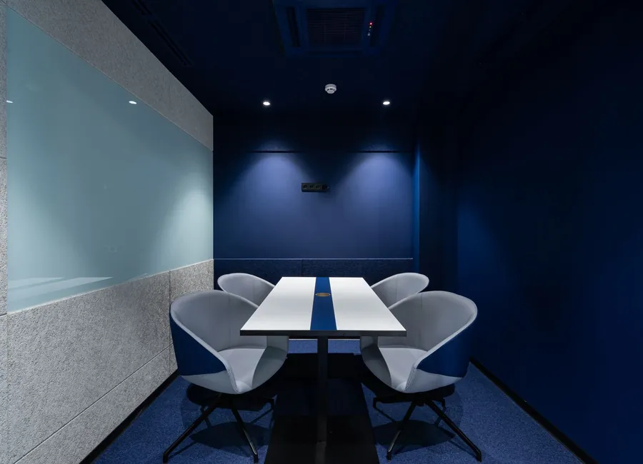 Comfortable chairs placed on carpet at long white desk in modern conference room with blue walls in contemporary business center