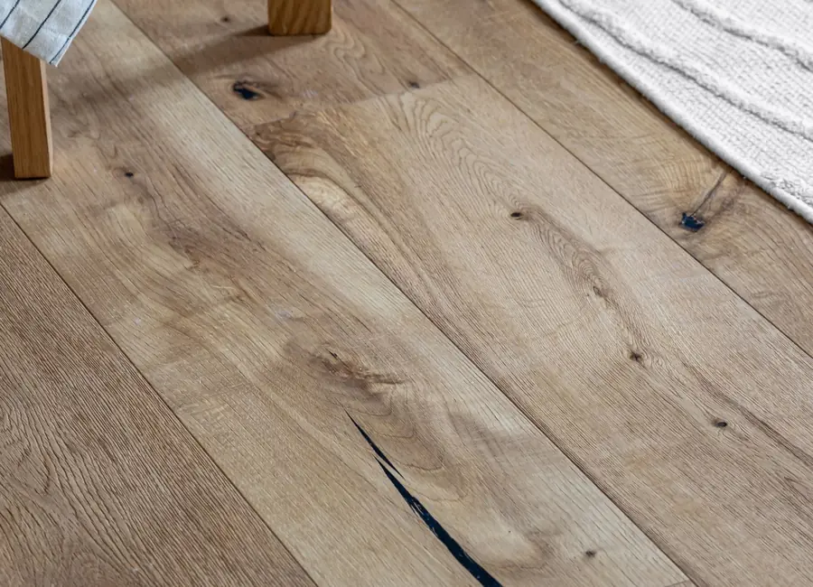 High angle view of natural wooden plank flooring next to a cozy woven rug.