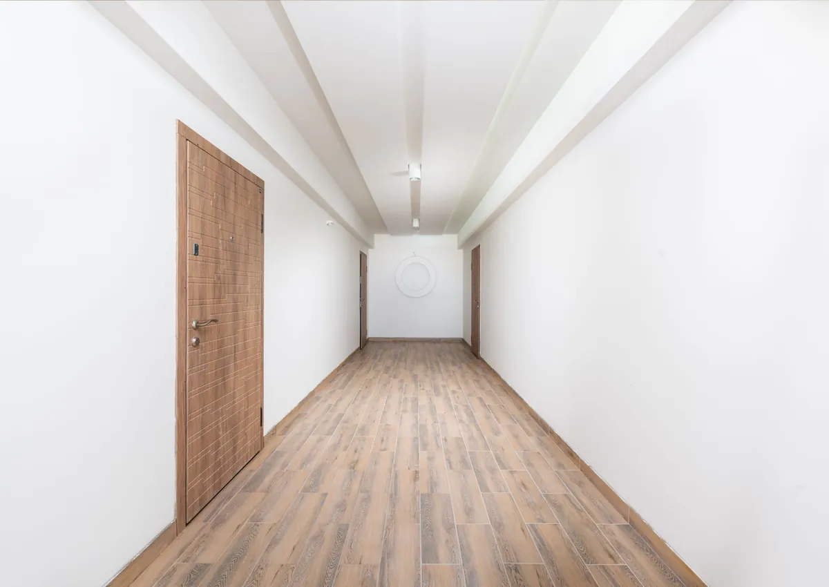 Clean white hallway with wooden flooring and contemporary doors, showcasing minimalism.