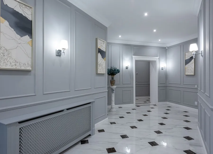 Interior of corridor of contemporary villa with shiny tiled floor and gray walls decorated with paintings and lamps