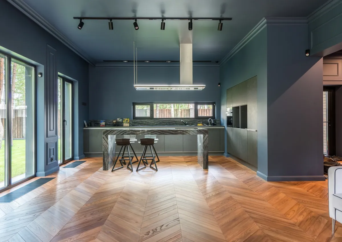 Spacious modern kitchen featuring chevron parquet flooring and sleek design.