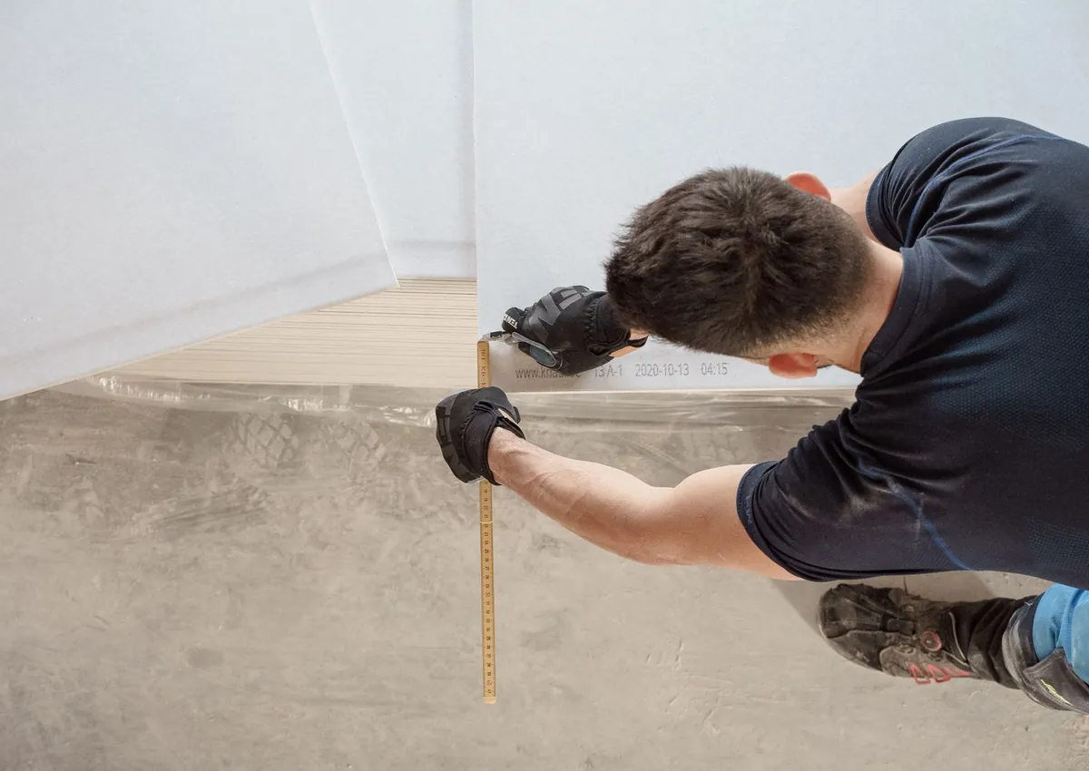 Construction worker measuring and cutting flooring panels in a renovation project.
