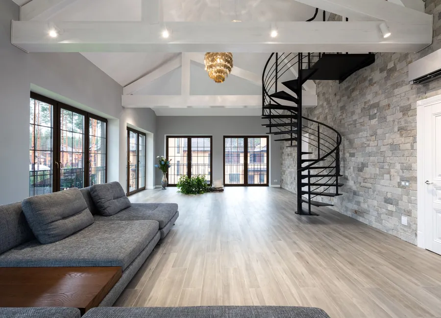 Contemporary living room with curvy black stairs and large windows in bright daylight