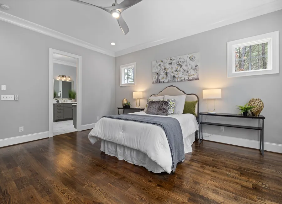 Spacious modern bedroom featuring neutral tones, elegant decor, and hardwood floors.
